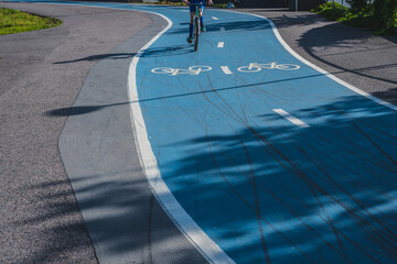 Cyclist riding on curved blue bicycle path.