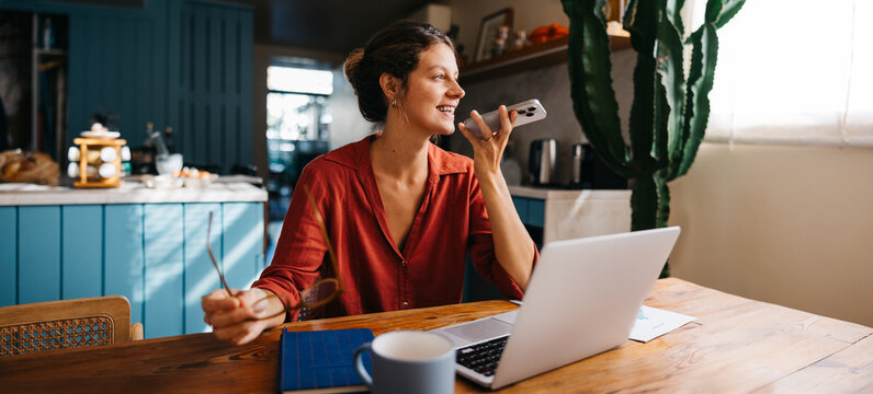 Fototapeta Woman chats on phone at home office