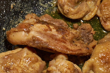 Pieces of chicken meat are fried in a frying pan, exuding flavor and mouth-watering appearance. Delicious chicken pieces are fried in a frying pan until golden brown.