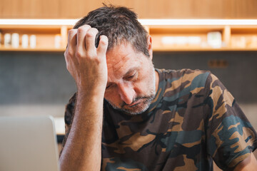 Portrait of depressed mature adult male wearing camouflage army shirt, concept of military war veteran