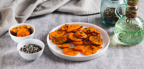 Pieces of fried carrots with garlic and herbs on a plate on the table web banner