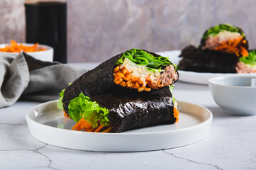 Tuna, cheese, Korean carrots and lettuce wrapped in nori on a plate on the table