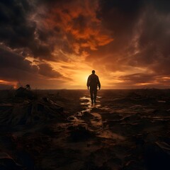 Fototapeta premium Silhouette of a lone figure walking towards the sunset in a desolate landscape filled with dark clouds and a fiery sky creating a sense of hope and resilience
