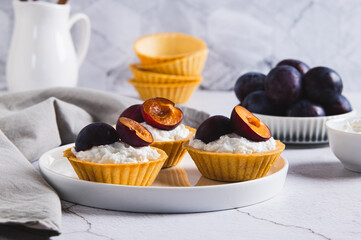 Mini tartlets with cottage cheese and plum on a plate on the table