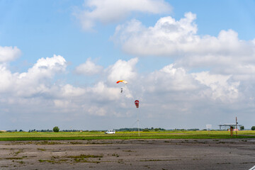 Skydivers landing on airfield in distance