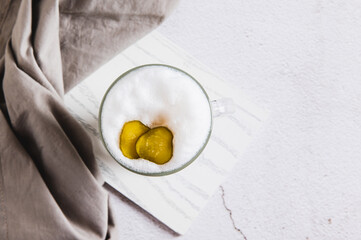 Close up of latte with pickles in a glass and pickles in a bowl on the table top view
