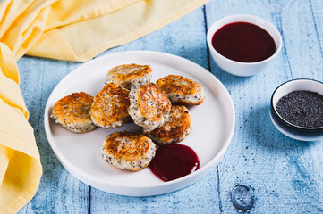 Small cottage cheese pancakes with poppy seeds on a plate on the table