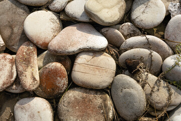 A collection of smooth, rounded stones in various shades of gray and beige. Some stones have a...