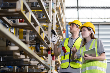 Female and male workers use tablet working in metal car part warehouse, import export, logistic...
