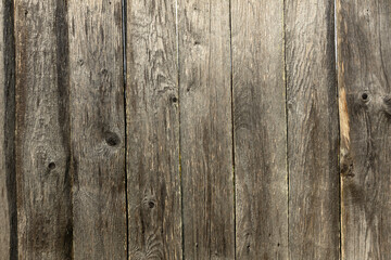 Fototapeta premium A close-up view of weathered wooden planks with a rustic texture. The wood shows signs of aging, with knots and varying shades of brown and gray.