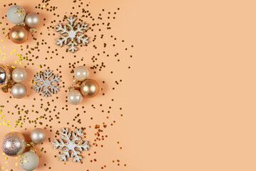 Top view vertical photo featuring variety of tree adornments, baubles, shimmering stars, snowflake accents, confetti on pastel backdrop holiday greetings or advert