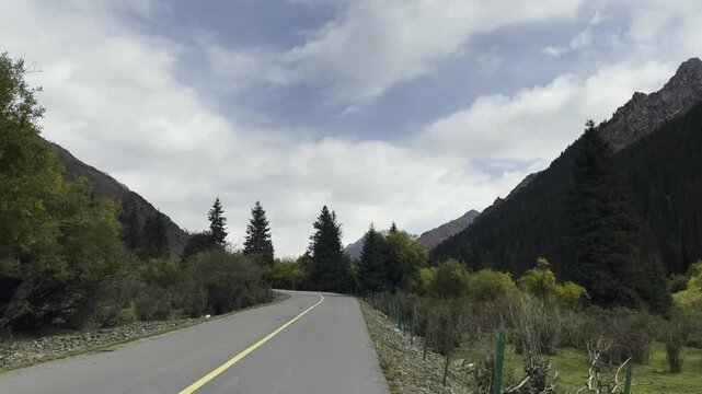 vehicle traveling on winding rural road in xinjiang, china