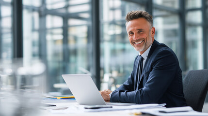 Confident businessman smiling at laptop in modern office workspace