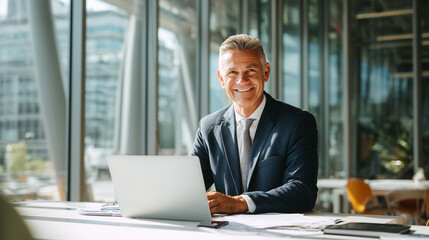 Confident businessman smiling at laptop in bright modern office workspace