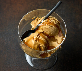 caramel ice cream scoop with sauce in glass bowl