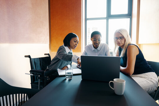 Diverse group of women collaborating in an office setting with a wheelchair user
