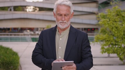 Confident mature businessman in suit working on digital tablet outside office building, representing modern business lifestyle and technology - Powered by Adobe