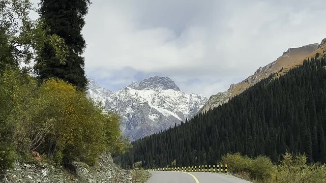 vehicle traveling on winding mountain road in xinjiang, china