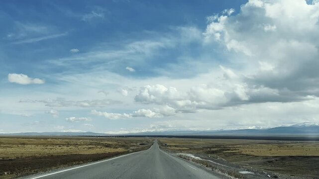 vehicle traveling on straight road leading to snow mountain in the distance, xinjiang, china