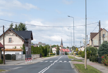 Residential suburb street with cityscape of Drezdenko, Lubuskie, Poland with traditional houses, greenery, and view towards church spire—typical small city suburban scene