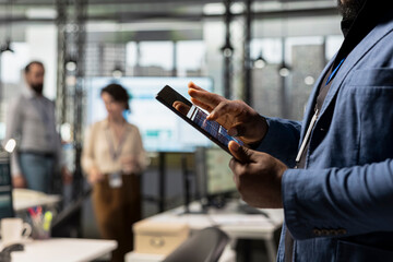 Close up of african american expert uses digital tools for KPI analytics to build a new vision, reviewing performance data insights on tablet for goals achievement in a modern office environment.