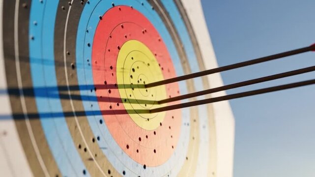 Arrows hitting bullseye on archery target representing success, achievement, and precision in competitive sport against a clear blue sky