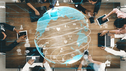A diverse team collaborates around a wooden table with laptops and devices. The globe visual symbolizes global communication and technological innovation in today workspace. Xenic