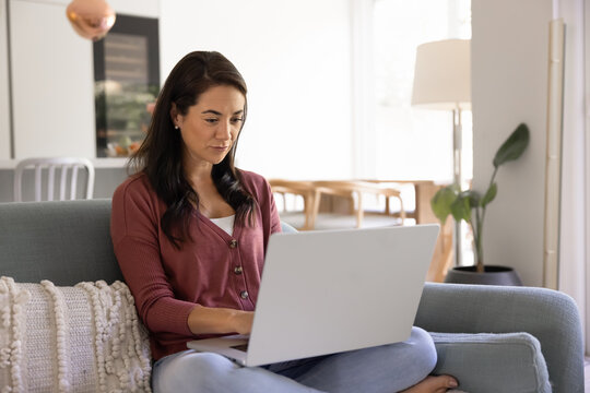 Focused young Latin homeowner woman using domestic Internet communication
