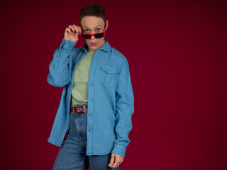 Fototapeta premium Person holding red sunglasses looking curiously over glasses