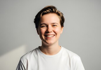 Smiling Person in White T-Shirt Against Gray Background — Natural Portrait with Soft Lighting and Warm Expression