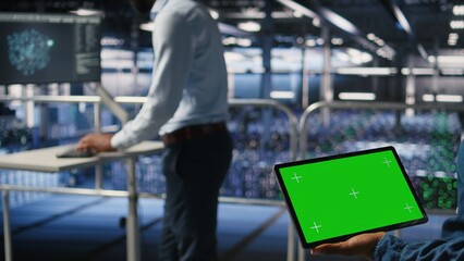 Server hub engineers finetuning configurations using chroma key device. Close up of technicians on data center industrial platform analyzing performance outputs on isolated screen tablet,