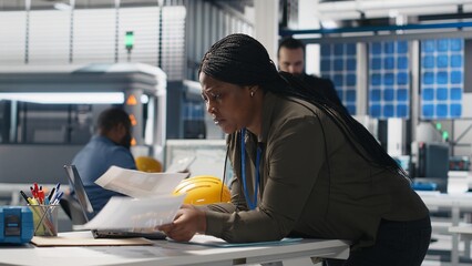 General manager reviewing production line system in a solar facility used for manufacturing,...