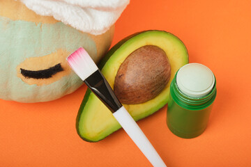 Avocado mask stick concept, pumpkin and avocado on an orange background, autumn beauty care