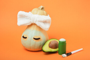Avocado mask stick concept, pumpkin and avocado on an orange background, autumn beauty care