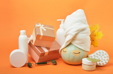 Pumpkin, gift boxes and various cosmetics on an orange background, holiday gift-giving and sales concept, autumn self-care