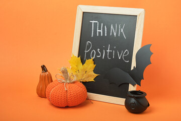 Halloween decor and chalkboard with the inscription "Think Positive" on an orange background