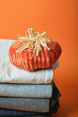 Stack of jeans of different colors on orange background, autumn clothing sale concept