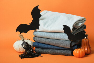 Halloween decor and a stack of jeans of different colors on an orange background, autumn sale of Halloween clothes