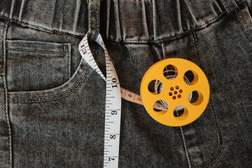 Measuring tape and jeans on an orange background, the concept of fighting excess weight in the autumn period