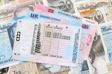 United Kingdom driving license with residence permit card on UK money close up