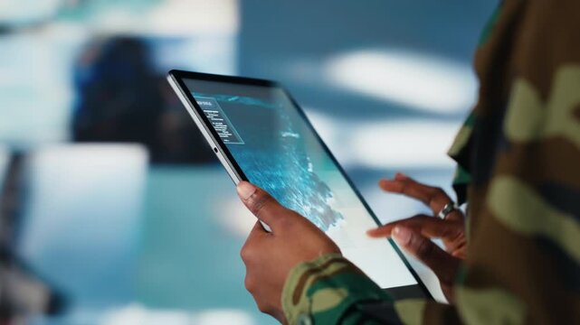 Soldier using warning system software on tablet in control room to monitor incoming enemy aerial attacks. Army agent maintains air space superiority with radar during armed conflict, close up