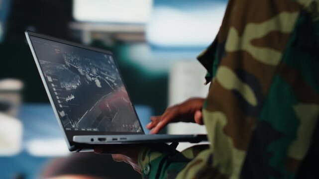 Soldier in command center housing missile defense system using laptop in front of multimedia backdrop. Woman in armed forces headquarters tracking rockets using radar systems on notebook, close up