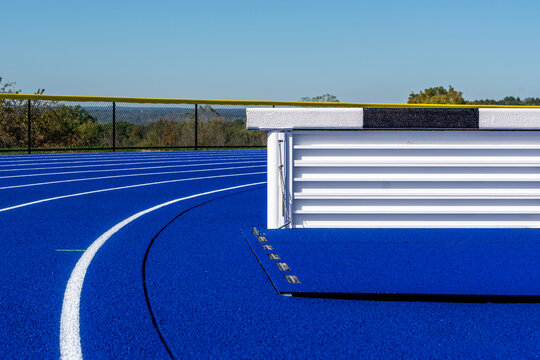 Close up photo of a steeplechase jump on a new blue running track.