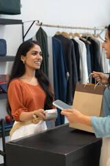 Obraz premium Happy retail professional woman offering POS terminal to customer