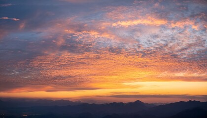 Fototapeta premium Morning sky with glowing altocumulus clouds and distant mountains at sunrise 