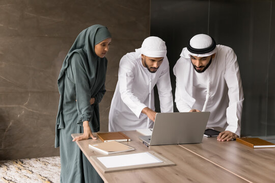 Young Arab man mentor teach diverse Muslim colleagues using notebook