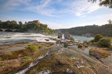 Majestic Rhine Falls cascading near historic castle at sunset