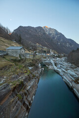 Scenic river flows through rocky landscape near small village at dusk