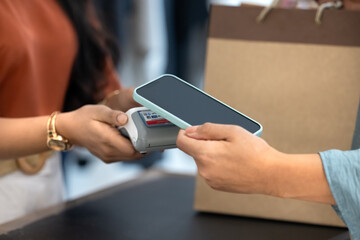 Cropped shot of boutique customer using NFC service on cellphone