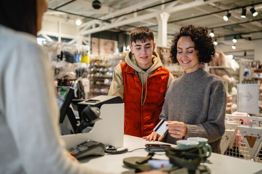 Mother and son paying with credit card at retail store checkout